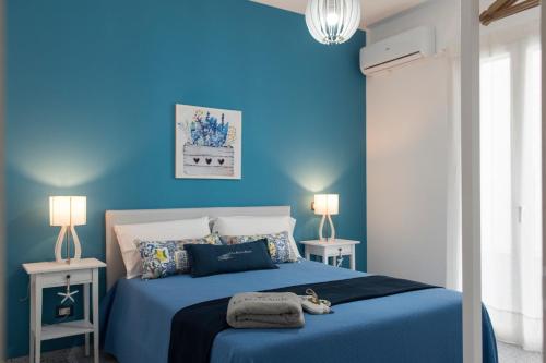 a blue bedroom with a bed with a blue wall at La Scala Suite in Realmonte