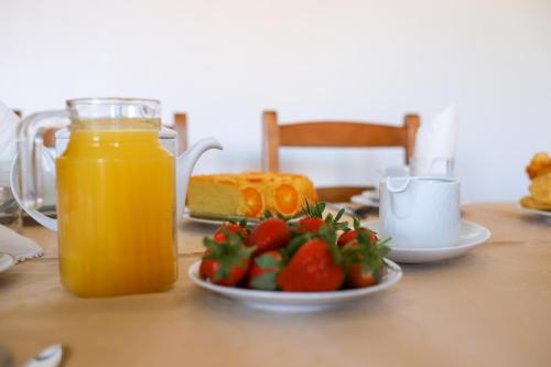 a table with a plate of fruit and a jar of orange juice at Casas da Lagariça in Sortelha