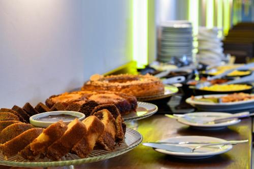 a table topped with cakes and plates of food at Littoral Gold Flat in João Pessoa