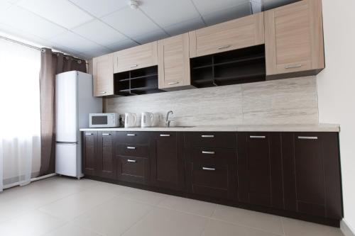 a kitchen with brown cabinets and a refrigerator at Гостиница Полет in Syktyvkar