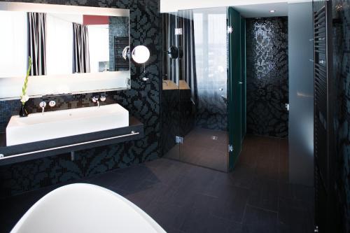 a bathroom with a sink and a mirror and a shower at Mövenpick Hotel Stuttgart Airport in Stuttgart
