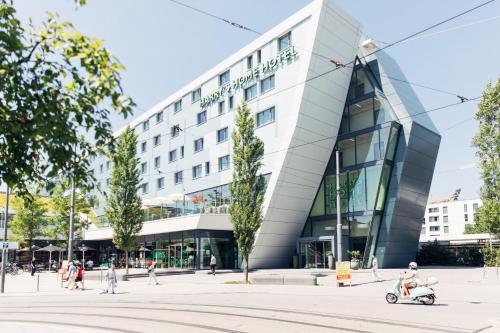 a man riding a scooter in front of a building at harry's home hotel & apartments in Munich