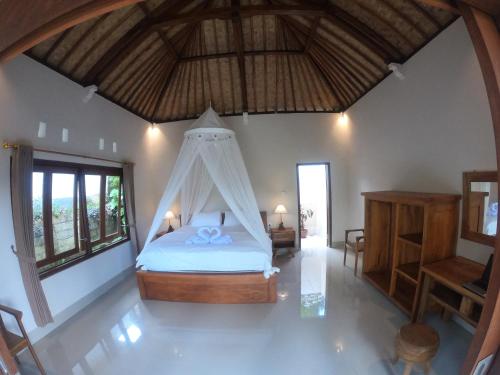 a bedroom with a bed in a room with windows at Rumah Sidemen in Sidemen