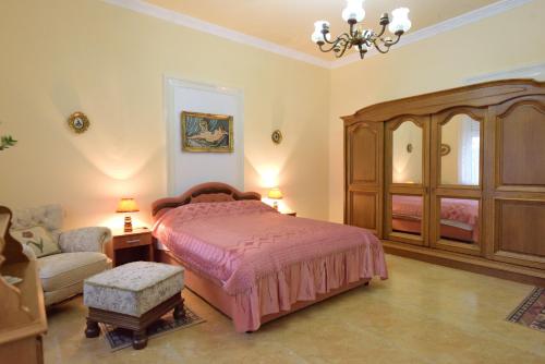 a bedroom with a bed and a chair and a couch at Apartman Vila Milica in Kikinda