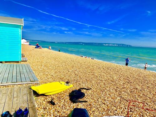 a beach with a blue building and a yellow umbrella at Forest beach Shorefield Park in Lymington