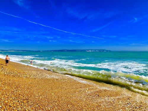 two people walking on a beach with the ocean at Forest beach Shorefield Park in Lymington