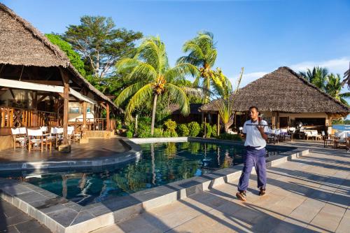 a man standing next to a swimming pool at a resort at Corail Noir Hotel in Ambaro