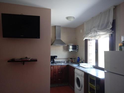 a kitchen with a refrigerator and a tv on the wall at Casa Rural Al-Mofrag y Apartamentos El Mirador de Monfragüe in Villarreal de San Carlos