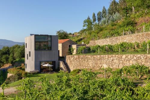 a house on a hill with a stone wall at Melgaço Alvarinho Houses in Melgaço