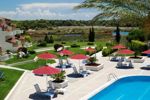 a resort with a pool and red umbrellas and chairs at Verde Al Mare Boutique Hotel in Kalogria