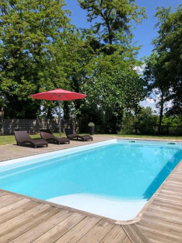 - une piscine avec un parasol rouge, des chaises, une table et un parasol dans l'établissement Along The River, à Bergerac
