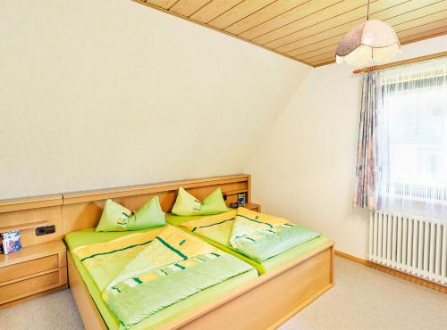 a bedroom with a bed with green pillows and a window at Ferienwohnung Haus Barbara in Bräunlingen