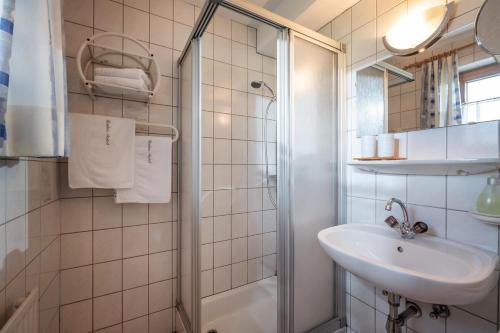 a white bathroom with a sink and a shower at Gästeheim Auwitsch in Mayrhofen