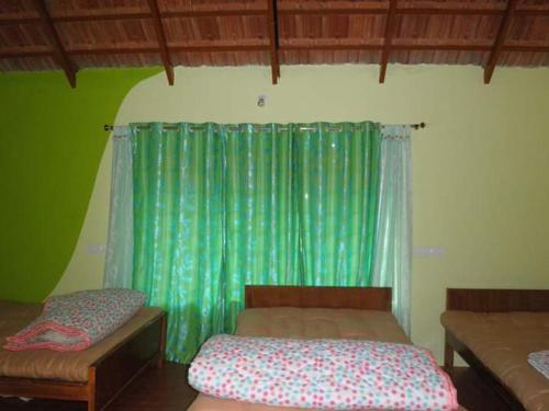Cette chambre comprend 2 lits et un rideau vert. dans l'établissement Vamoose Clover Leaf, à Chikmagalur