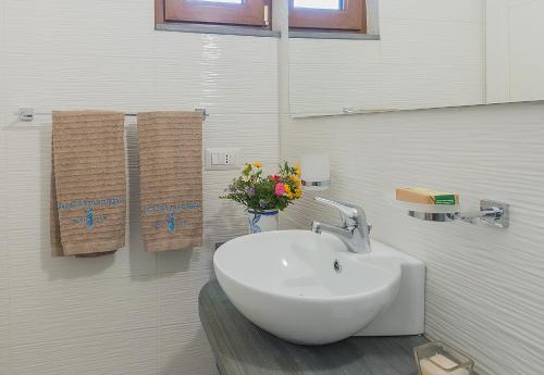 uma casa de banho com um lavatório e um vaso de flores em Nitrodi Thermal Relais em Ischia