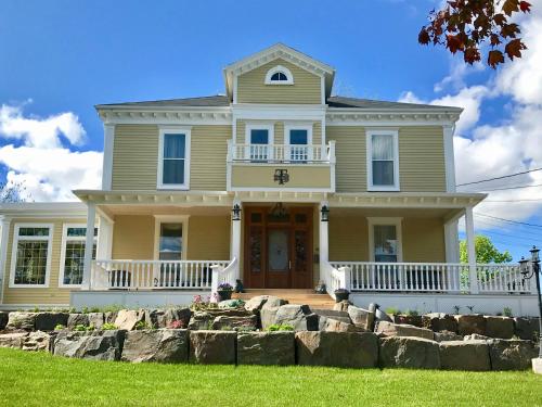 a large yellow house with a rock wall at Tattingstone Inn in Wolfville