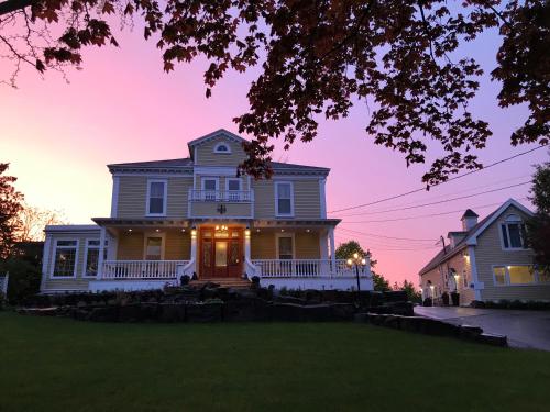 a white house with a front porch at dusk at Tattingstone Inn in Wolfville