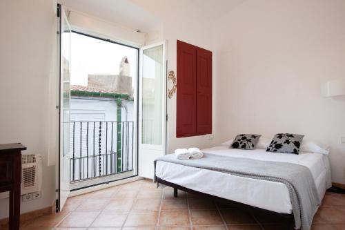 sypialnia z łóżkiem i dużym oknem w obiekcie Akira Flats Cadaqués Llané w mieście Cadaqués