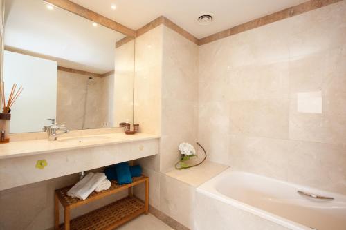 een badkamer met een wastafel, een bad en een spiegel bij Akira Flats Diagonal Mar Apartments in Barcelona