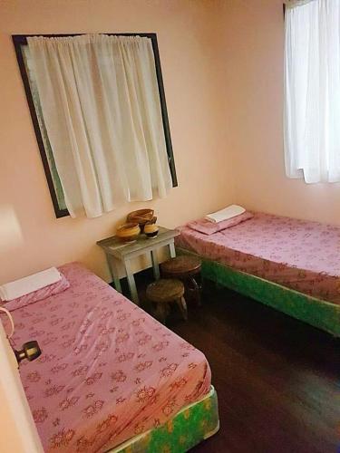 a room with two beds and a table and a window at P&M Traveler's Inn in Banaue