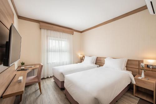 a hotel room with two beds and a television at Intercity Itupeva in Itupeva
