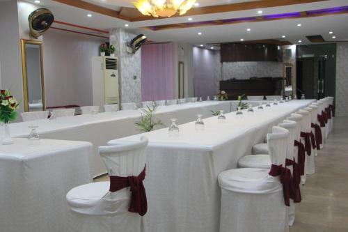 a long table with white tables and chairs in a room at Hotel The Leschanze in Lahore