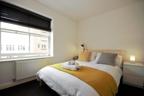 a bedroom with a bed with a yellow blanket and a window at HU1 City Centre Hub (sleeps 6) in Hull