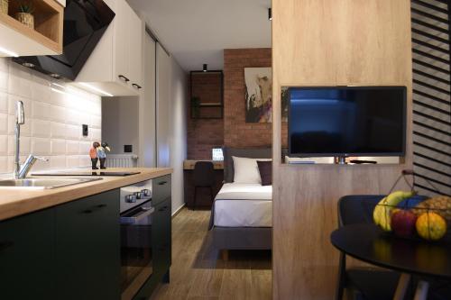 a kitchen with a living room with a bed and a television at Q Luxury Rooms in Thessaloniki