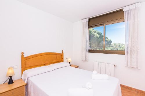 a white bedroom with a bed and a window at HomeHolidaysRentals Corts in Tordera