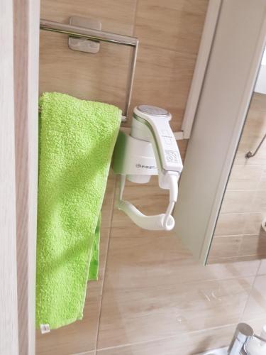 - une serviette verte et un sèche-cheveux dans la salle de bains dans l'établissement Apartment Centar LUX, à Banja Luka