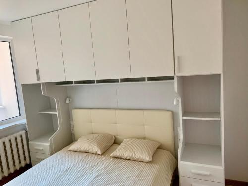 a bedroom with a bed with white cabinets at Alytus Apartament in Alytus