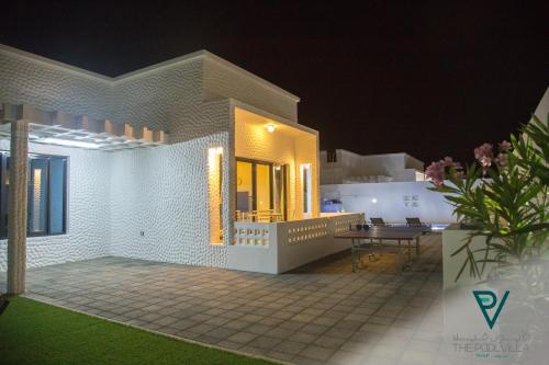 a white house with a patio at night at THE POOL VILLA - TANUF in Nizwa