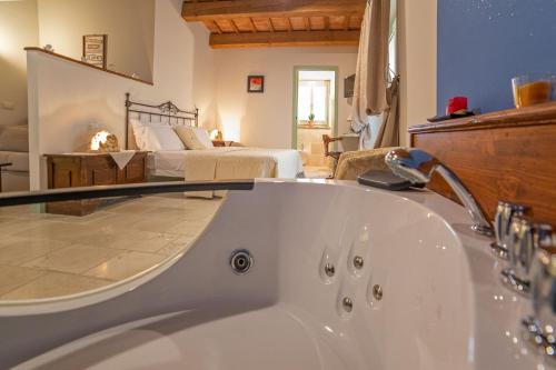 a bathroom with a bath tub and a bedroom at Le Maraclà Country House in Iesi