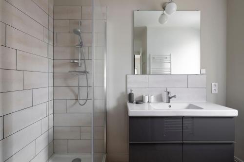 ein Bad mit einem Waschbecken und einer Dusche mit einem Spiegel in der Unterkunft Harmonie by Cocoonr in Nantes