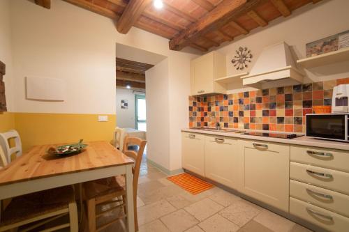 a kitchen with white cabinets and a wooden table at Le Maraclà Country House in Iesi
