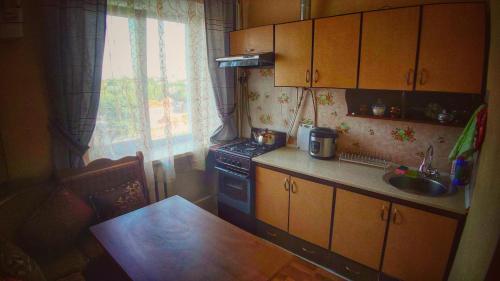 uma cozinha com um fogão, uma mesa e uma janela em квартира на вулиці Лесі Українки em Uzyn
