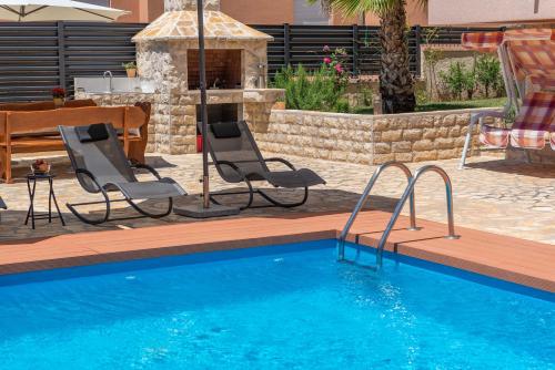 een zwembad met 2 stoelen en een tafel en een tafel bij Apartment Maja with private pool in Sveti Petar