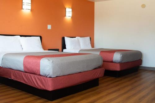 two beds in a hotel room with orange walls at Motel 6-Brinkley, AR in Brinkley