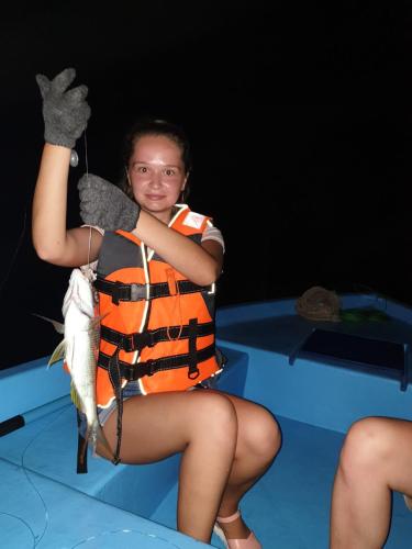 a girl in an orange life vest holding a fish at Thoddoo Beach Holiday in Thoddoo