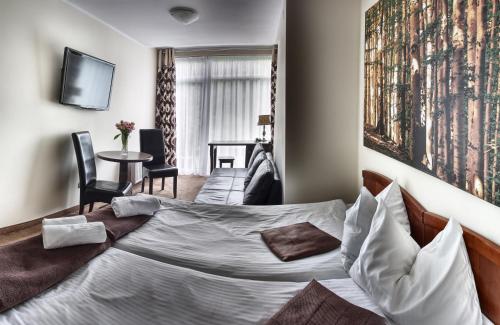 ウストロンにあるMazowsze Medi Spaのベッドとテーブルが備わるホテルルームです。