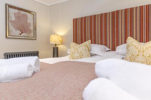 two beds in a hotel room with white sheets and pillows at Trewornan Manor in Wadebridge