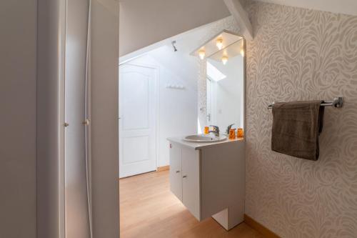a white bathroom with a sink and a mirror at Le Félix Grat - LAVALOC in Laval