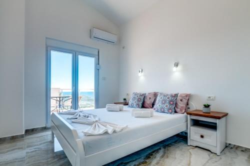 a white bedroom with a bed and a large window at Dolaca Villas in Sutomore