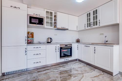 a white kitchen with white cabinets and appliances at Dolaca Villas in Sutomore