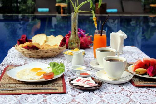 a table with plates of breakfast foods and cups of coffee at Moloppor Villa in Battambang