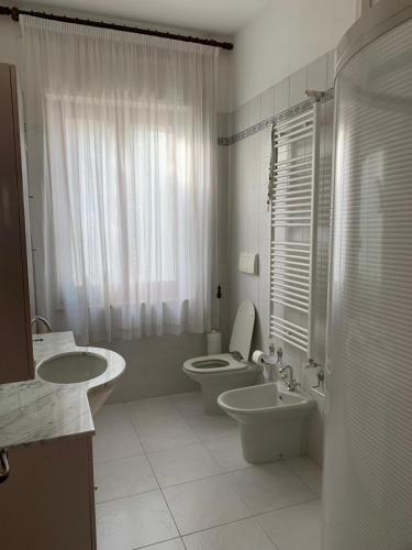 a white bathroom with two toilets and a sink at Casa Ohana in Serramanna