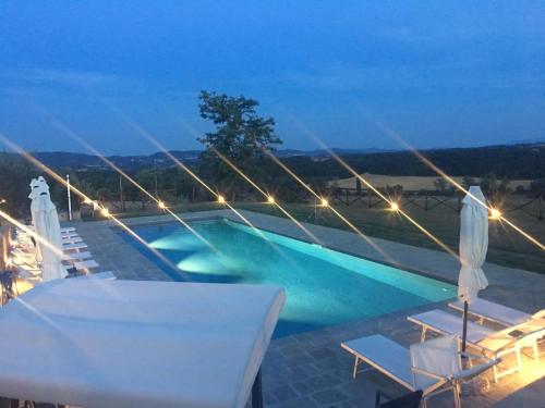 a swimming pool at night with chairs and lights at Agriturismo Melariano in Castelnuovo Berardenga