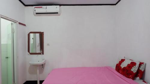 龙目岛库塔Perwita Homestay的卧室配有粉红色的床和水槽