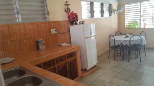 a kitchen with a white refrigerator and a table at Casa El pescador in Playa Larga
