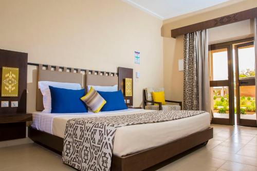 a bedroom with a large bed with blue and white pillows at Dunia Hôtel Ouagadougou Loumbila in Loumbila